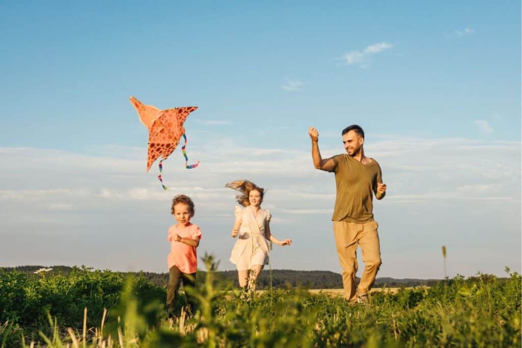 Happy Feels Good. How To Be Happy. Family Outside Flying A Kite.