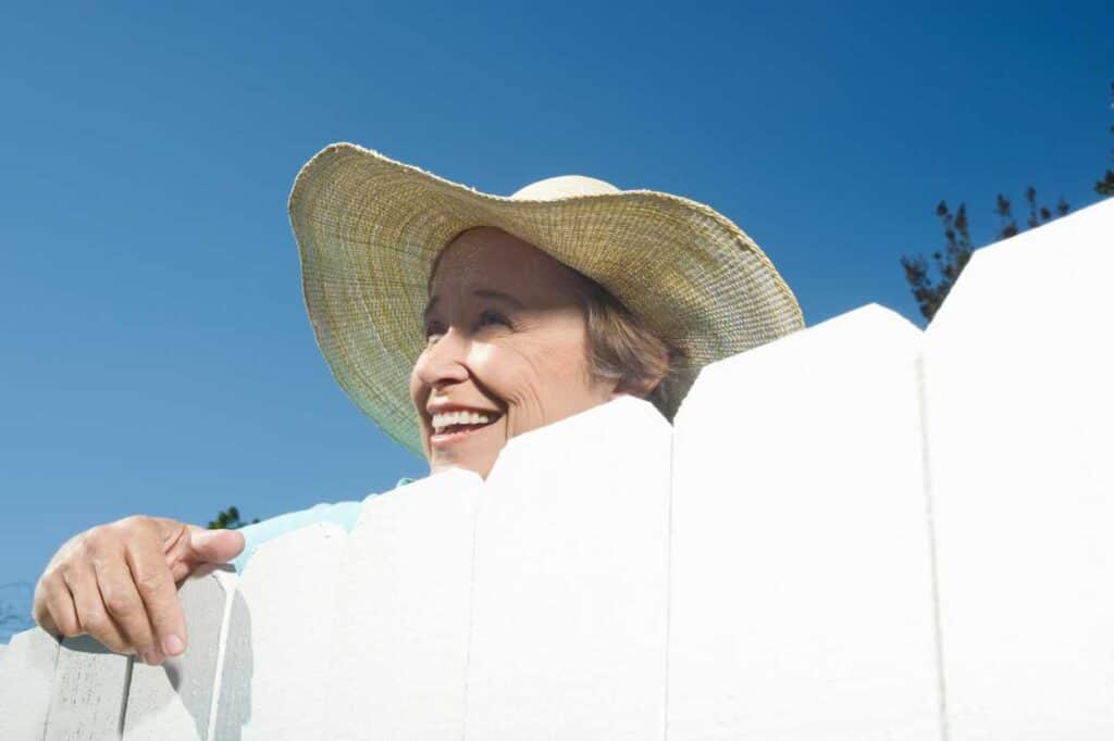 Happy Neighbor Lady Smiling Over Fence. There's More Than 2 Sides Of The Simple Neighborhood Fence