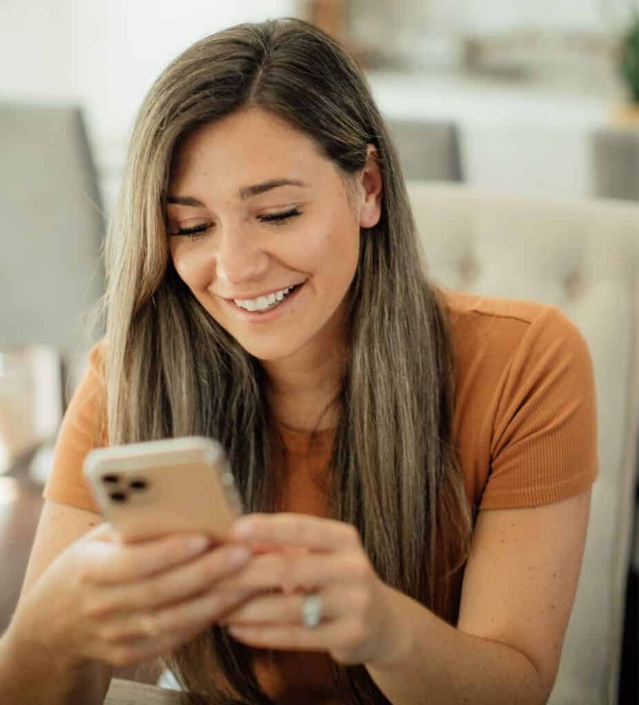 Smiling Woman Looking At Cell Phone